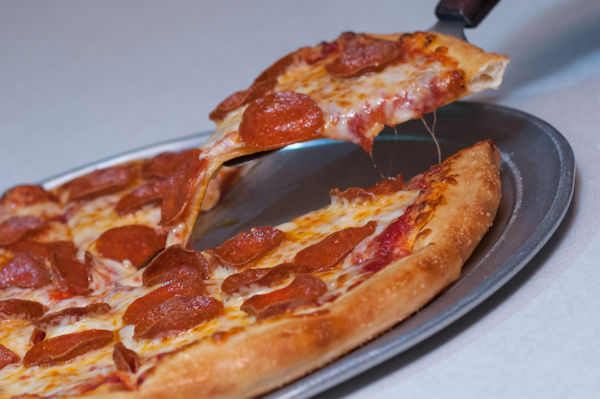 Pepperoni Pizza Slice being pulled from a pizza Pie on a pan